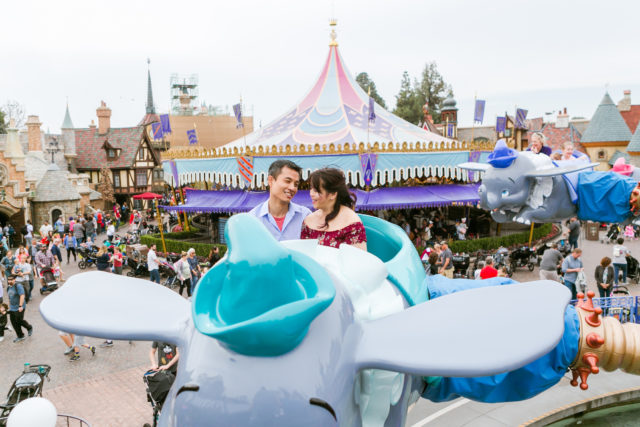 Couple posing for engagement photos in on Dumbo ride in fantasyland at Disneyland