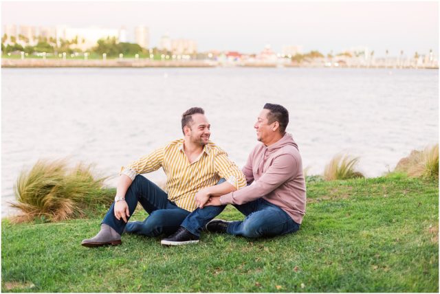 Grooms posing on rock cliff overlooking the marina in Long Beach at sunset.