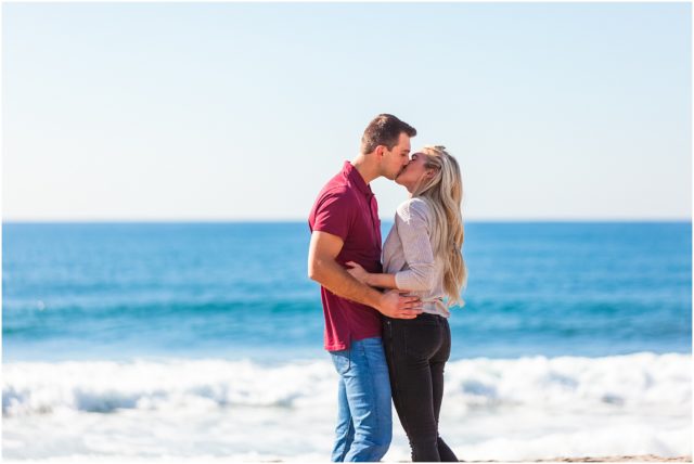 Newly engaged couple kissing on beach