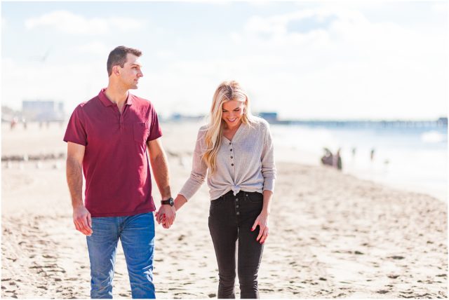 Newly engaged couple holding hands on beach