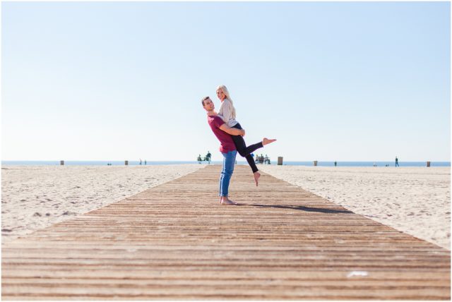 Newly engaged couple posing for their surprise beach engagement session in Santa Monica in the sand