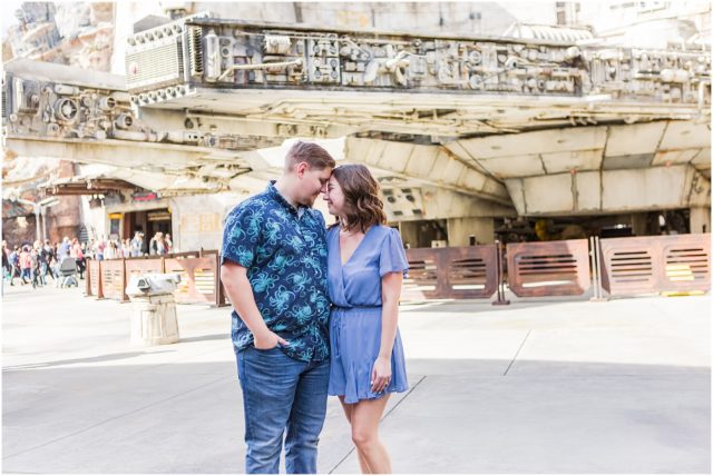 Couple posing for engagement session  in Galaxy's Edge with Millennium Falcon  at Disneyland Park.