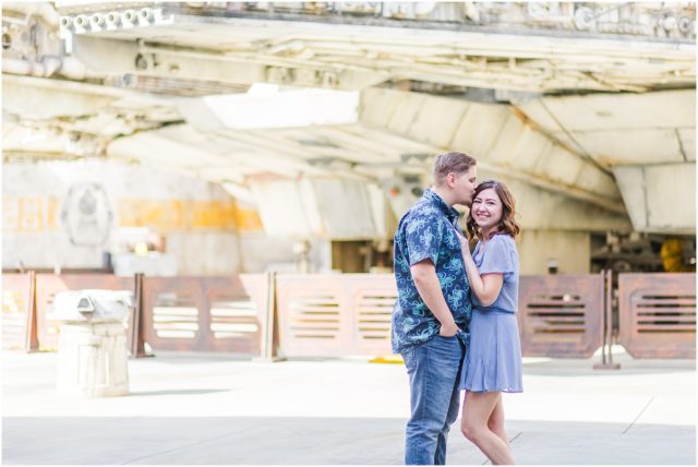 Couple posing for engagement session  in Galaxy's Edge with Millennium Falcon  at Disneyland Park.