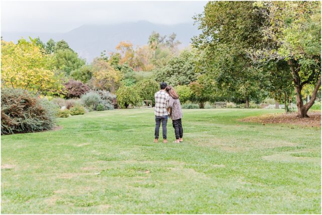 Man proposing to his girlfriend at La Arboretum in Arcadia with mountains in the background. 